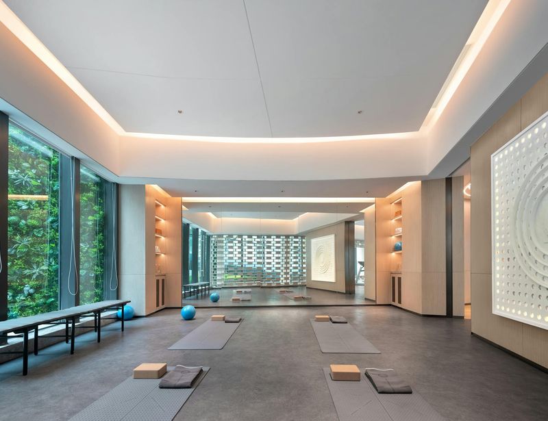 Spacious yoga studio with natural wood floors and green accents.